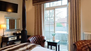 Une chambre à coucher avec un grand lit, une commode, un miroir, une fenêtre avec des rideaux et une vue sur l’extérieur.