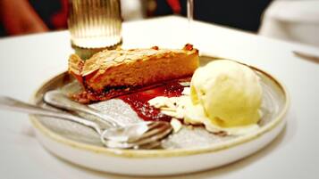En desserttallerken med et stykke tærte, en kugle is og et glas rødvin.
