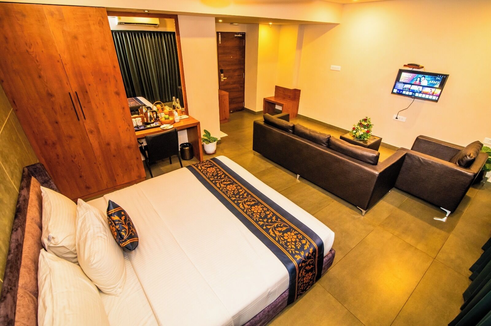 A hotel room with a bed, a desk, a sofa, and a TV.