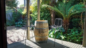 A wooden barrel with the inscription "Killicrankie" in a garden setting with two wire mesh chairs and a wooden deck. - The Conductor's Quarters (Bendigo)