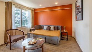 A room with a bed, a chair, a table with a tray, and a window with curtains.