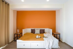 A bedroom with a white bed, orange walls, and a small table with a tray.
