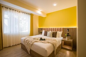 Una camera d'albergo moderna con un letto grande, una testiera in legno e un comodino con una lampada.