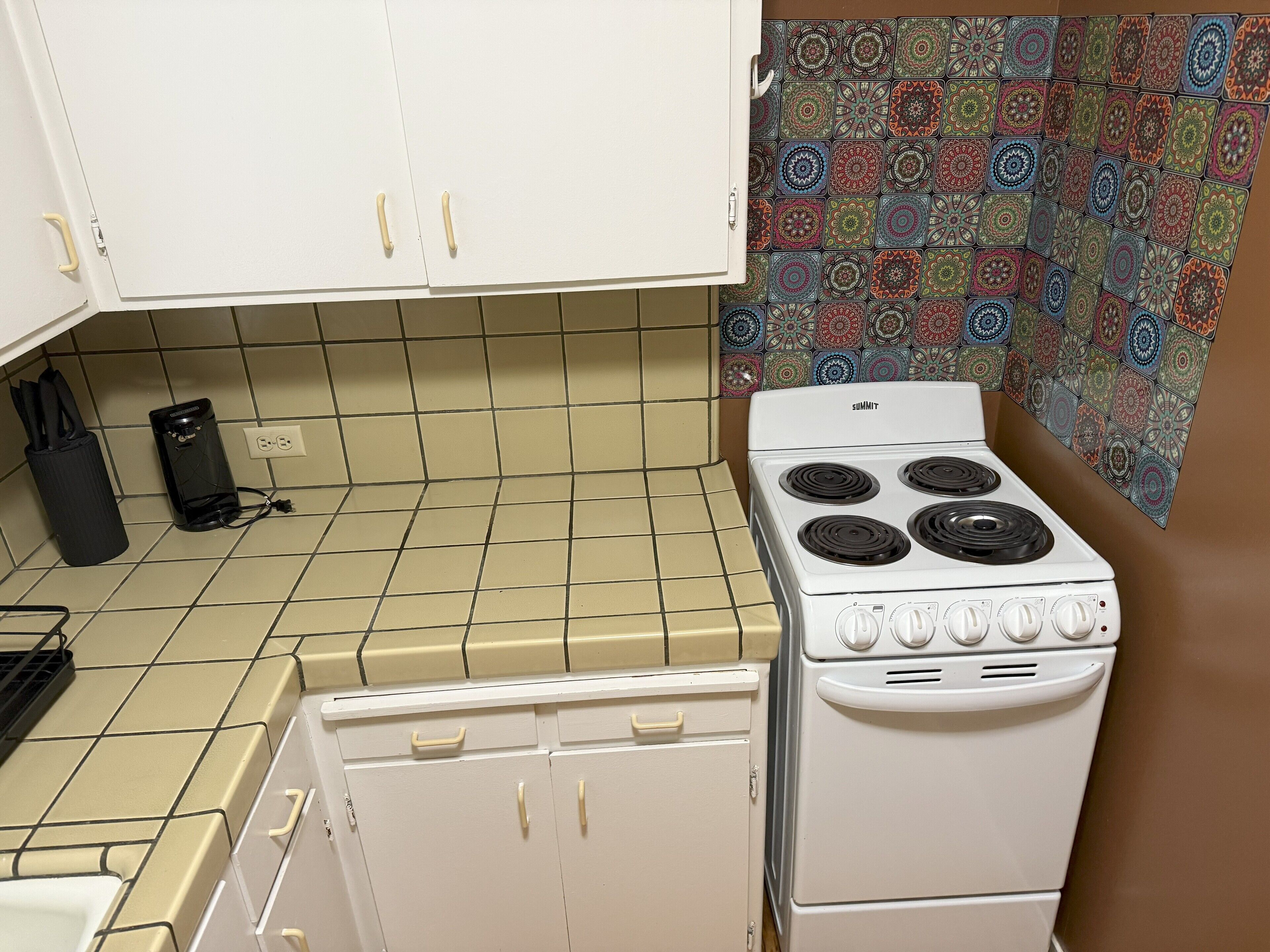 A kitchen with white cabinets, a white stove, and patterned tile backsplash.