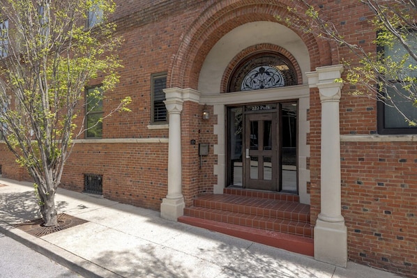 A brick building with a large arched entrance, a tree in front, and a sign reading '222 Polk.'