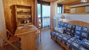 A wooden interior with a dining table, chairs, a sofa, and a window with curtains. - 50m from ski slopes, Ground floor, view parking, parking, tv, ski locker, 12m², Les 2 Alpes (Les Deux Alpes)