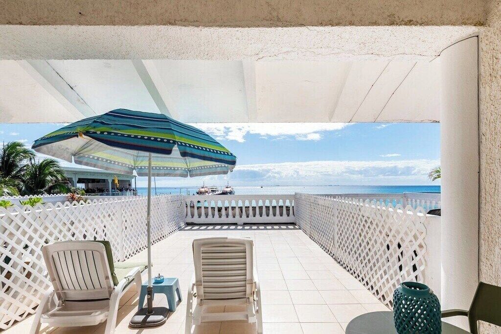 A balcony with two chairs, a table, and a decorative vase.