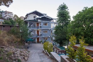 Un edificio de varios pisos con balcones, una escalera y un camino que lleva a una zona de piscina.