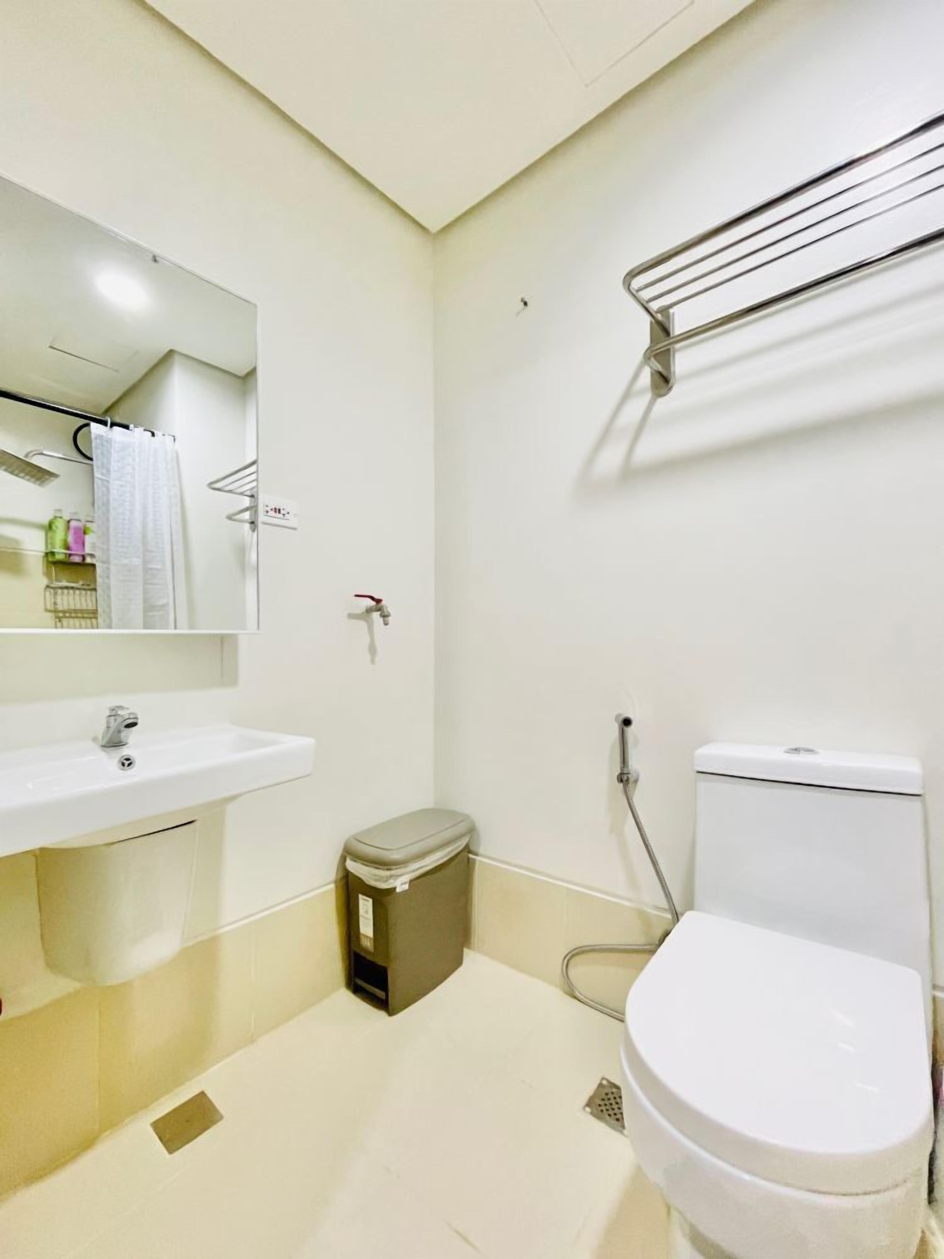 A small, clean bathroom with a white sink, mirror, toilet, and shower.
