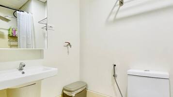 A small, clean bathroom with a white sink, mirror, toilet, and shower.