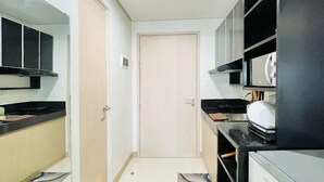 Une cuisine de taille réduite, équipée d’un réfrigérateur, d’une cuisinière et de meubles de couleur noire.