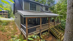 A two-story house with a covered porch and a staircase leading to a deck. - Pinewood Forest: 3BR Cabin with Hot Tub & Game Room (Sevierville)