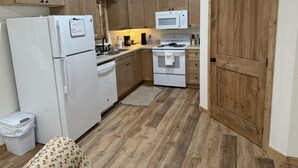 A compact kitchen with wooden cabinets, a white refrigerator, a microwave, and a stove.