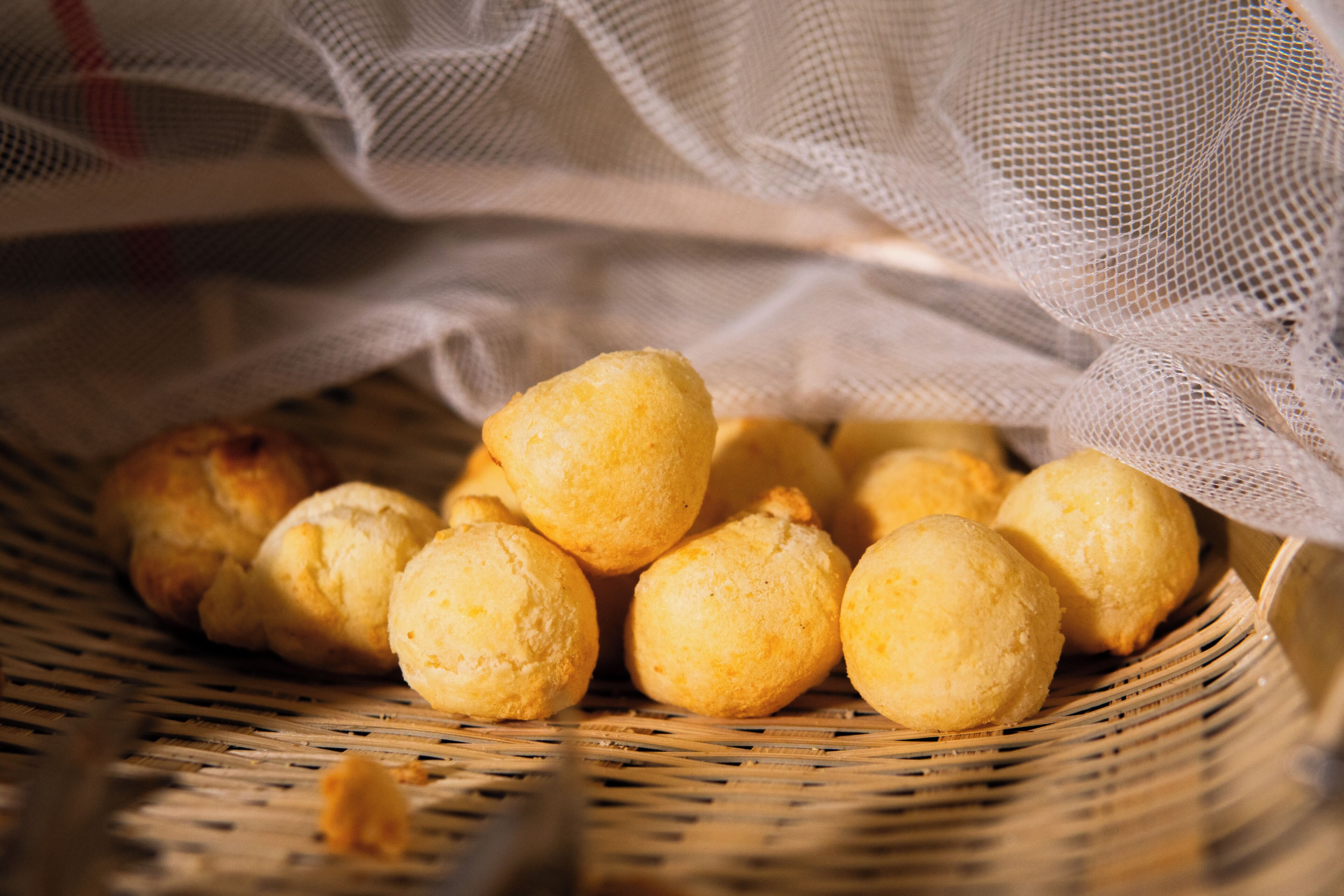 Un panier rempli de viennoiseries rondes, dorées et légèrement brunes.