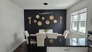 A dining area with a dark wall, a chandelier, and decorative plates. - Modern Family Retreat w/ Office & Fast WiFi (East Hartford)