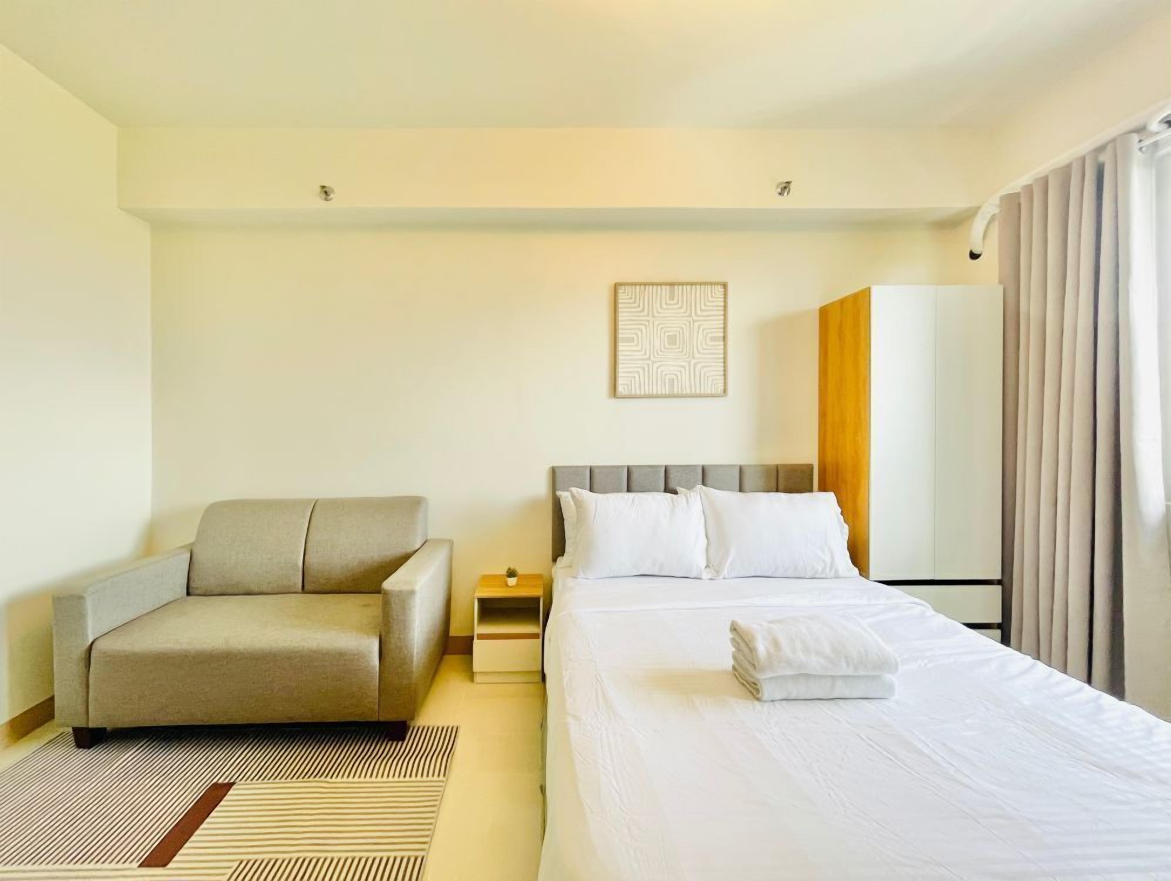 Ett hotellrum med en säng, en soffa, ett sängbord och ett konstverk som hänger på väggen.