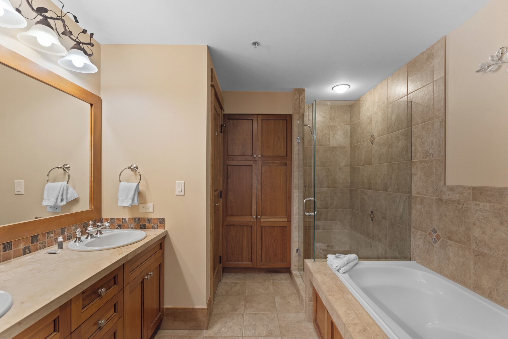 Un baño moderno con tocador de doble lavabo, cabina de ducha con mampara de vidrio y bañera independiente.