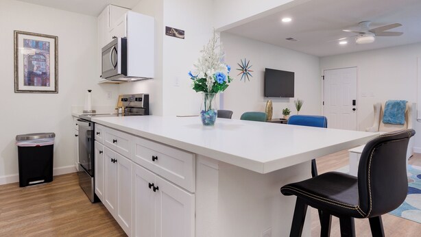 Una cocina moderna con armarios blancos, una isla central y un taburete negro.