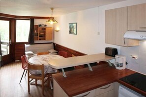 A compact kitchen with a dining area, wooden cabinets, a coffee maker, and a built-in microwave.