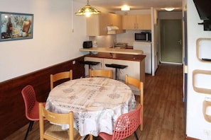 A compact kitchen with wooden cabinets, a microwave, and a small dining area with a table and chairs.