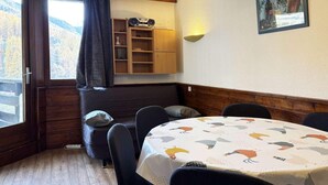 Un coin repas accueillant avec une table ronde, des chaises, un buffet en bois et une fenêtre agrémentée de rideaux.