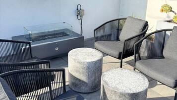 Eine Dachterrasse mit Sitzgelegenheiten im Freien, einem Whirlpool mit Glasabdeckung und einem Schild, das die maximale Personenzahl angibt.
