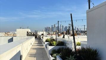 Une terrasse sur le toit offrant une vue dégagée sur les gratte-ciel de la ville, avec des bâtiments modernes et une promenade dallée.