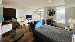 Une chambre d’hôtel moderne équipée d’un lit, d’une télévision, d’un bureau, d’une chaise et offrant une vue sur la ville.