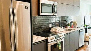 Une cuisine moderne équipée d’appareils électroménagers en acier inoxydable, d’un four à micro-ondes et d’un plan de travail en granit.
