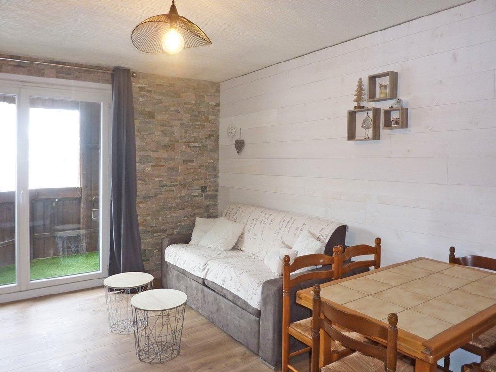 Un salon chaleureux avec un canapé, une table à manger et deux petites tables rondes.