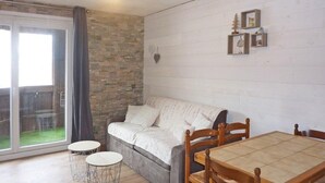 Un salon chaleureux avec un canapé, une table à manger et deux petites tables rondes.