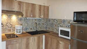 Une cuisine avec des meubles de rangement en bois, un évier, un four à micro-ondes et une machine à café.