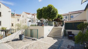 A courtyard with cobblestone flooring, a staircase, and a covered seating area with outdoor furniture.