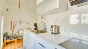 A compact kitchen with a sink, a kettle, and a dishwasher.