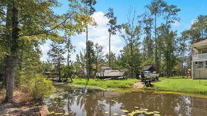 A lakeside cabin with a dock, surrounded by tall trees and a clear sky. - Waterfront 2BR/1BA – Fully Furnished Home in Covington, LA (Covington)