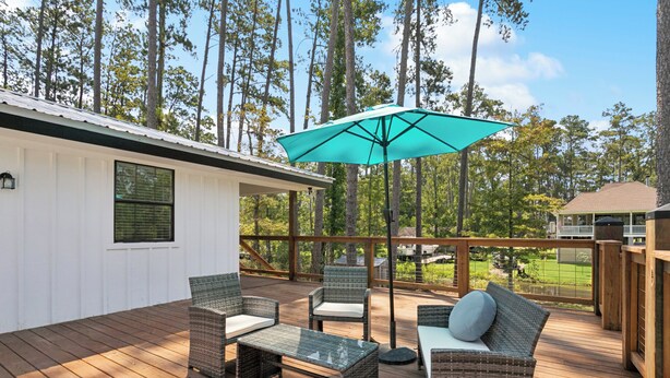 A wooden deck with wicker furniture, a table, and an umbrella. - Waterfront 2BR/1BA – Fully Furnished Home in Covington, LA (Covington)