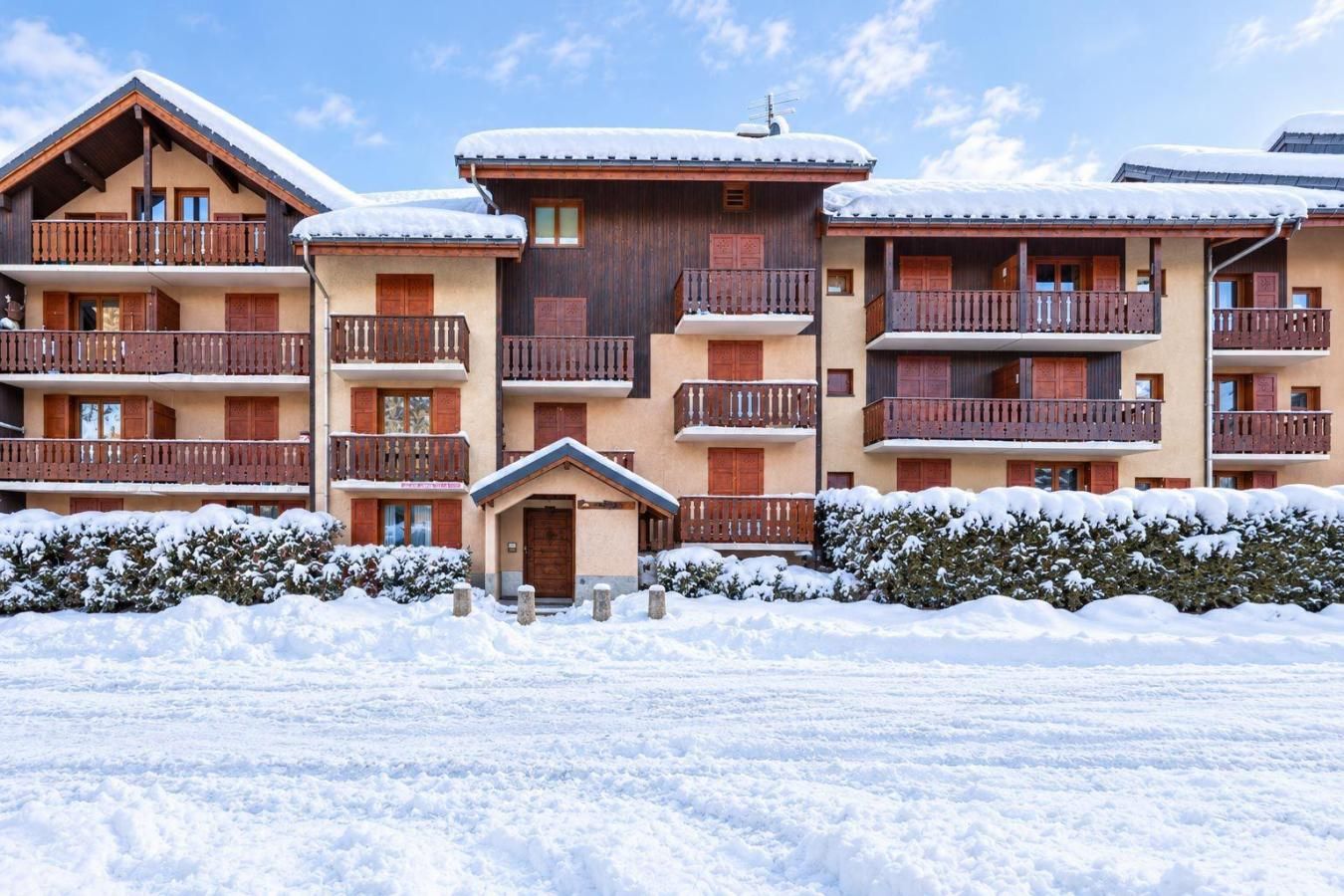 Een hotel met meerdere verdiepingen, houten balkon en sneeuw bedekte daken.