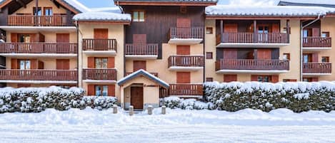 A multi-story hotel with wooden balconies and snow-covered roofs.