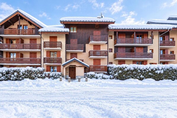 A multi-story hotel with wooden balconies and snow-covered roofs.