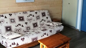 A wooden-paneled room with a sofa, a small wooden table, and a door with a blue trim. - 350m from ski slopes, Ground floor, terrace, parking, tv, ski locker, 24m², Valloire (Valloire)