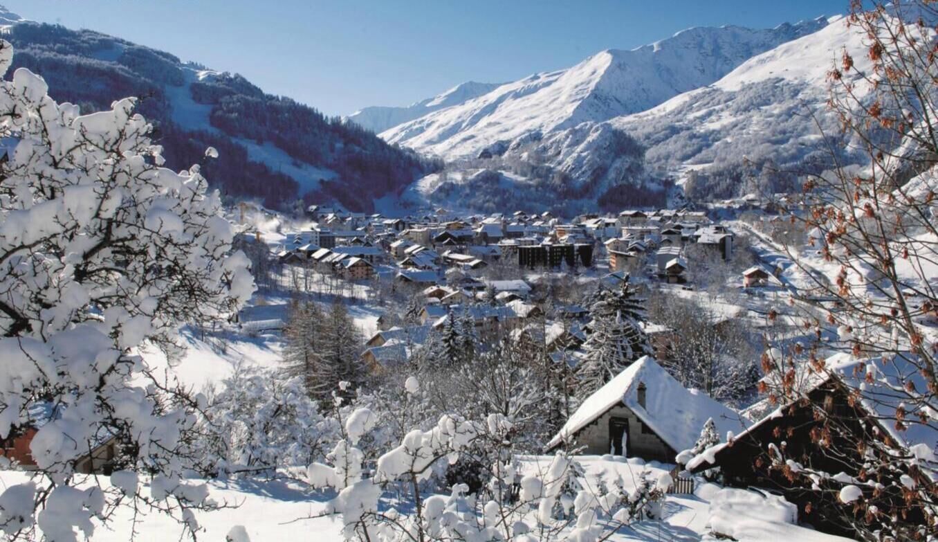 A snow-covered village with traditional buildings, surrounded by mountains.