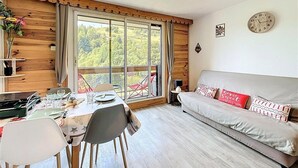 Um quarto acolhedor com uma mesa de jantar, cadeiras, um sofá e uma janela grande com vista para o verde.