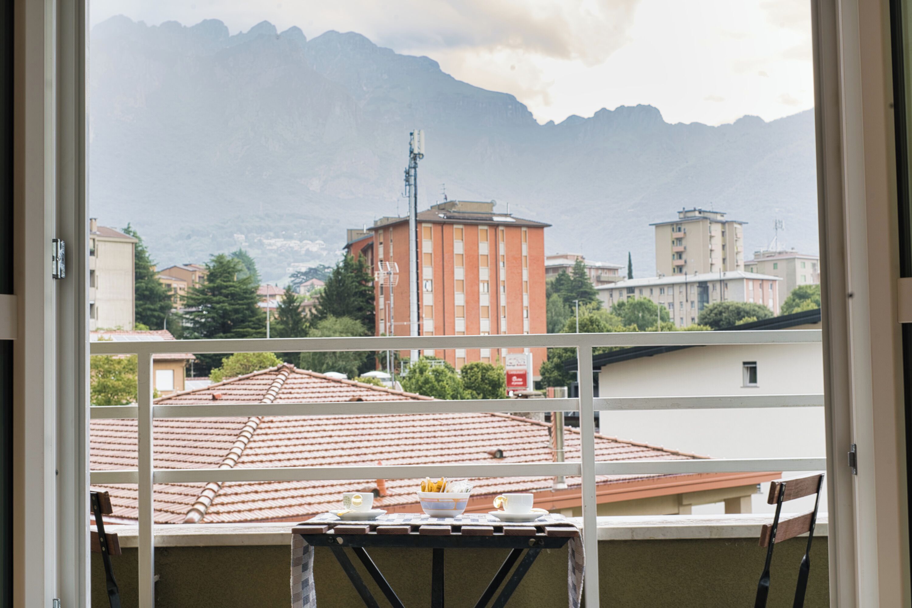 Un balcon avec une table, des chaises et une vue sur les bâtiments et les montagnes.
