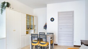 A dining area with a table and chairs, a wardrobe, a door, and a small plant.