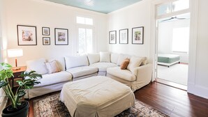 A spacious living room with a sectional sofa, a large ottoman, and a potted plant. - Treehouse views in Historic Downtown Thomasville, Georgia (Thomasville)