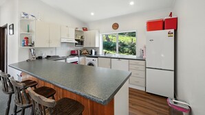 A modern kitchen with a granite countertop, white cabinets, a built-in oven, and a window with a view of greenery.
