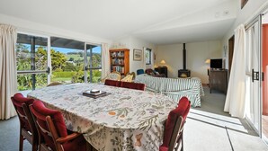 A dining area with a table set for four, a bookshelf, a fireplace, and a view of the outdoors.