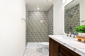 Un baño moderno con ducha, inodoro y tocador.