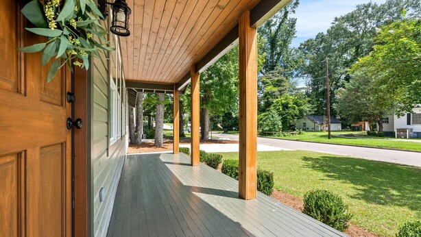 A wooden porch with a green railing, a hanging plant, and a street view in the background. - Gorgeous Auburn Getaway! BRAND NEW 3Bed/3Bath (Auburn)