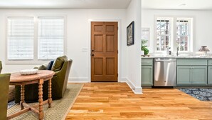 A modern kitchen with wooden flooring, green cabinets, and a stainless steel dishwasher. - Gorgeous Auburn Getaway! BRAND NEW 3Bed/3Bath (Auburn)